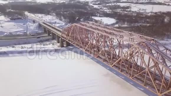 悬索式火车桥穿越冬河及车行雪道上的鸟瞰图火车铁路桥视频的预览图