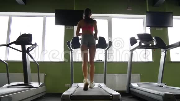 有魅力的混血女人在运动健身房的跑步机上跑步视频的预览图