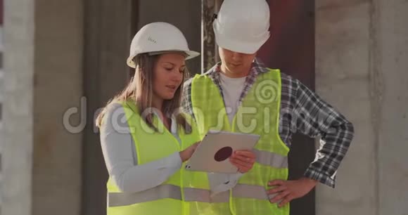 在脚手架施工计划或施工计划上讨论的团队或建筑师建筑工人或戴头盔的工人视频的预览图
