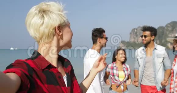女孩欢迎人们团体在沙滩上自助拍照手机快乐度假游客视频的预览图