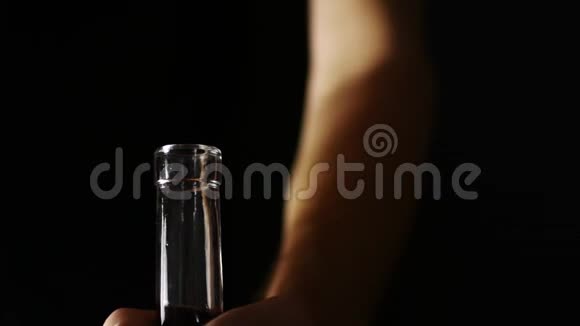 深色背景下的一瓶酒一个人手拿着瓶子倒酒视频的预览图