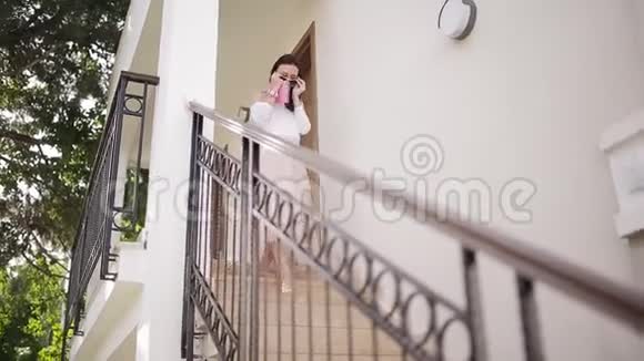 一个漂亮的女人手里拿着一块平板电脑走下楼梯视频的预览图