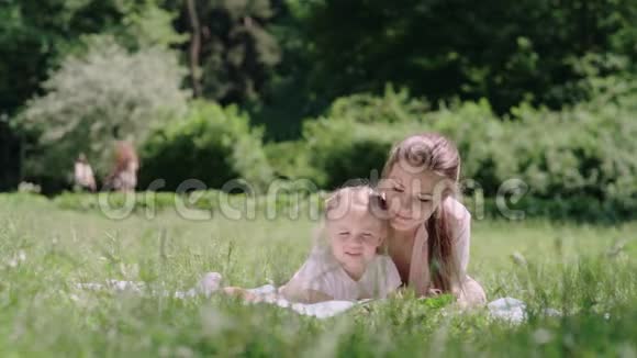 年轻的母亲和女儿在公园躺在草地上看书视频的预览图