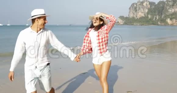 快乐的情侣在沙滩上牵手年轻的快乐男人和恋爱中的女人度假视频的预览图