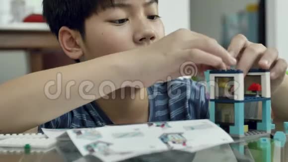 慢动作的亚洲男孩在家里玩塑料块与微笑的脸4K视频的预览图