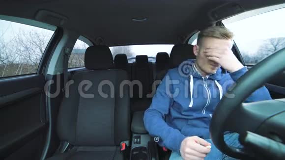 疲惫的年轻司机坐在车里用4K点了一支烟视频的预览图