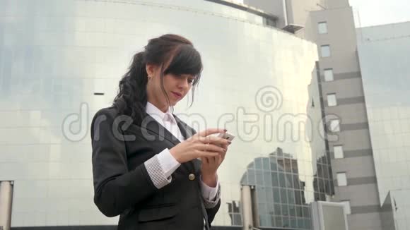 漂亮的女商人在办公楼前用数字平板电脑视频的预览图