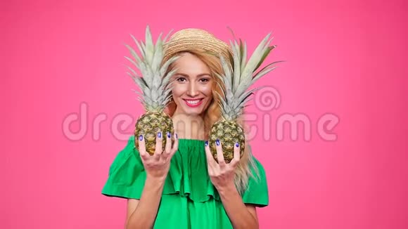 戴帽子的年轻女子戴着粉色背景的菠萝视频的预览图