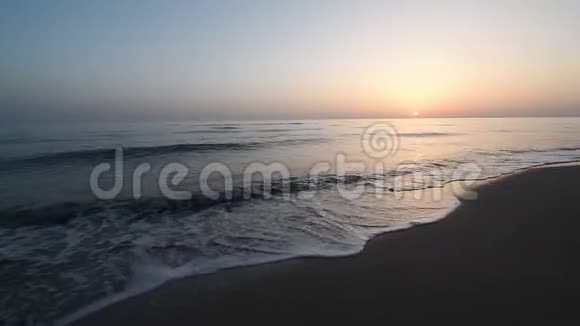在日落的桑迪海滩上海面掀起了一阵平静的巨浪海水中的太阳反射自然背景晚上视频的预览图