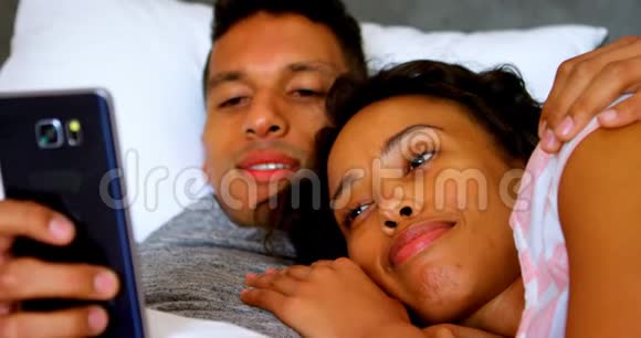 情侣在床上放松时使用手机视频的预览图