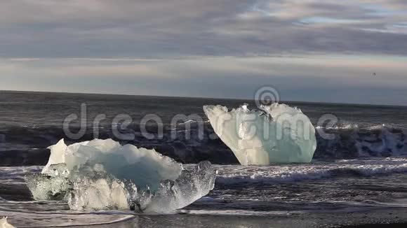冰山和一片蓝白冰卷在海浪上波浪在冰上破碎日出时在海滩冲浪冰岛斯隆视频的预览图