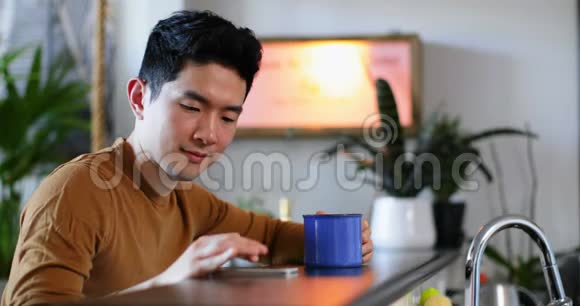 男人在厨房用手机喝咖啡视频的预览图