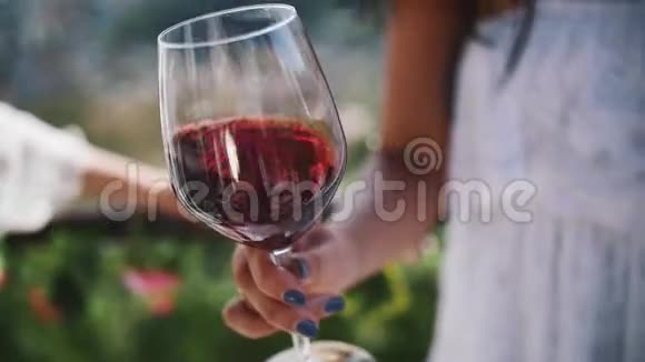 年轻女子的手在户外摇着一杯红酒视频的预览图