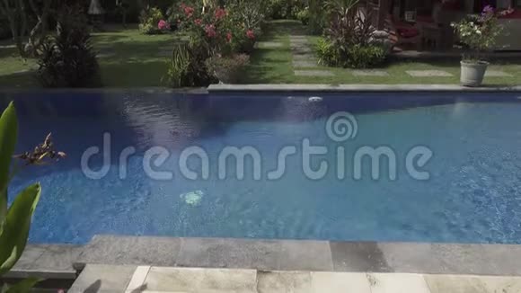 印度尼西亚巴厘岛阳光明媚的一天在蓝天的背景下观赏一个有游泳池和山脉的热带花园视频的预览图
