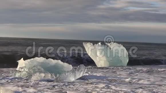 冰山和一片蓝白冰卷在海浪上波浪在冰上破碎日出时在海滩冲浪冰岛斯隆视频的预览图