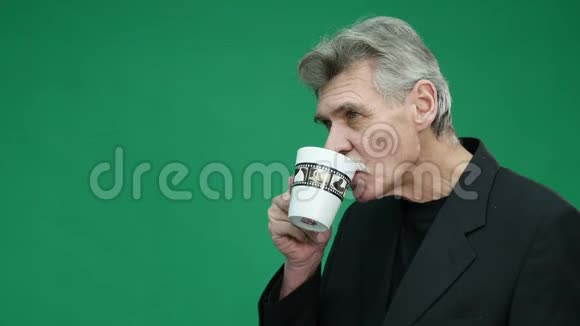 在绿色背景下喝杯咖啡的老人视频的预览图