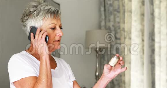 老太太拿着药瓶在卧室里打电话视频的预览图