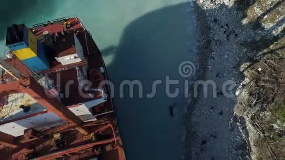 在美丽的蓝色海岸附近停泊着一艘空的红色的驳船一艘大工业飞船站在附近视频的预览图