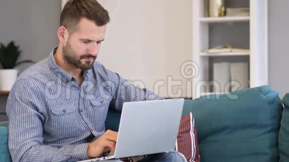 在卧室里用笔记本电脑工作的沉思的男人视频的预览图