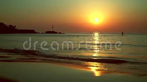 一个冲浪者的剪影在日落时游过从太阳到大海的小路视频的预览图