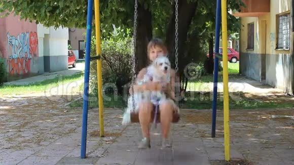 一个在秋千上抱着狗的女孩视频的预览图