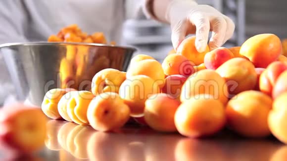 手拿糕点厨师切杏在工业厨房准备果酱视频的预览图