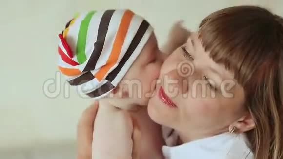 婴儿温柔地吻他的母亲穿着条纹短裤和帽子的婴儿视频的预览图