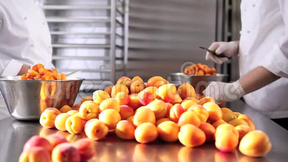 手拿糕点厨师切杏在工业厨房准备果酱视频的预览图