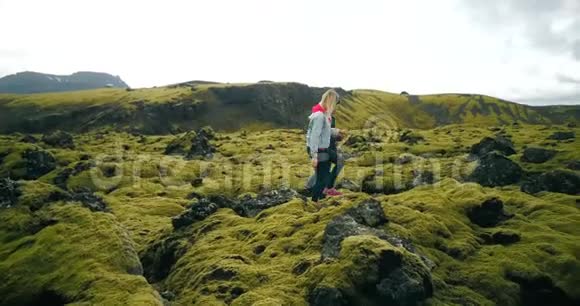 在冰岛火山熔岩上散步的年轻夫妇的鸟瞰图男人和女人享受风景视频的预览图