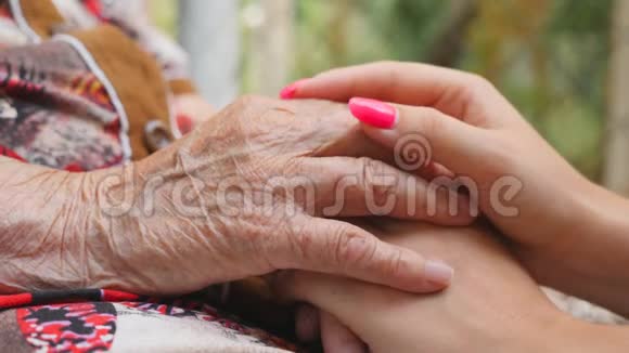 年轻的女性和皱纹的手安慰和抚摸对方户外孙女和祖母花时间视频的预览图