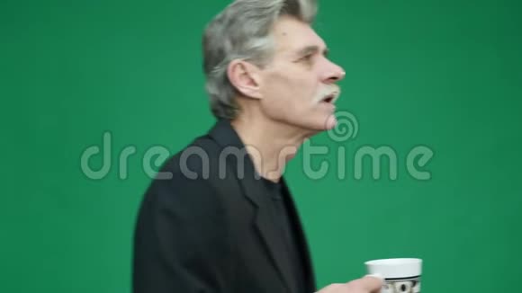 在绿色背景下喝杯咖啡的老人视频的预览图