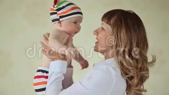 可爱的妈妈在玩她的孩子穿着条纹短裤和帽子的婴儿视频的预览图