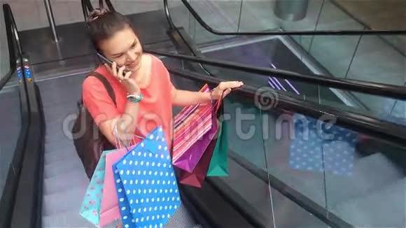 年轻女子打电话女孩在商场的自动扶梯上楼视频的预览图