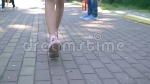 特写镜头女腿穿着时尚的粉红色运动鞋带着人行道走在街上的女孩自然阳光充足视频的预览图