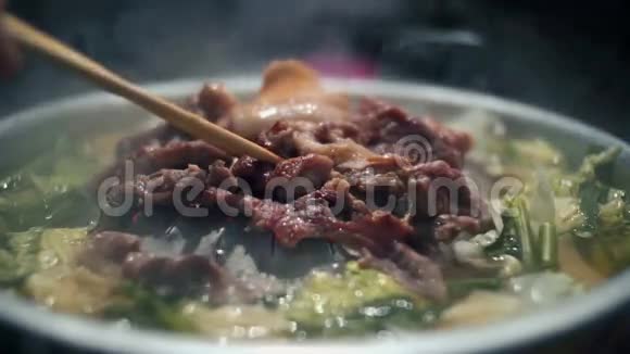 女人的手在热锅上翻着肉和烟韩国烧烤视频的预览图
