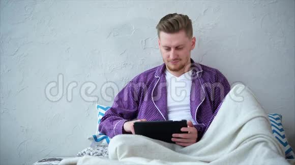 网购的男性顾客有平板电脑的人坐在床上视频的预览图