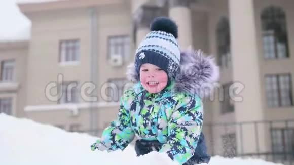 一个小孩子在雪山上玩扔雪笑晴朗的霜天新鲜空气中的乐趣和游戏视频的预览图