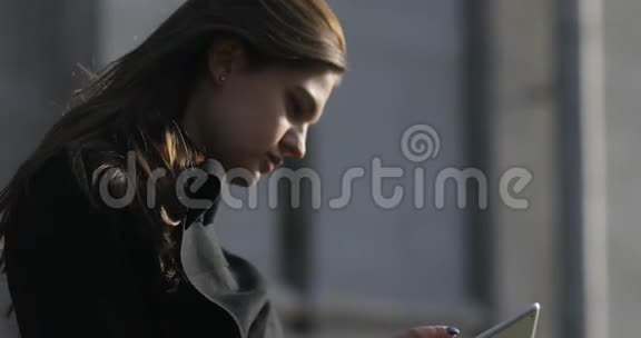 年轻的女商人在春天的一天里在外面的一个建筑工地上看着平板电脑头发随风飘扬视频的预览图