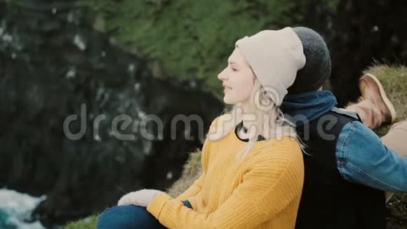 年轻的幸福夫妇坐在悬崖边休息游客男女欣赏美丽的风景视频的预览图