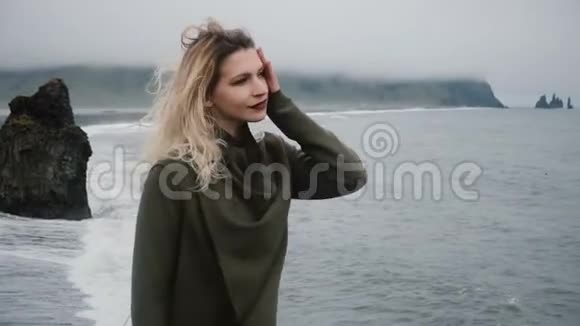 年轻美丽的女人独自站在海边欣赏冰岛巨魔脚趾的景色视频的预览图