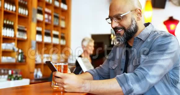 4k柜台边喝啤酒边用手机的快乐男人视频的预览图