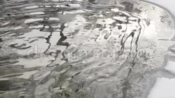 冬季水坑中树木和天空的抽象反射在浅水湖的底部看到石头慢慢慢慢视频的预览图