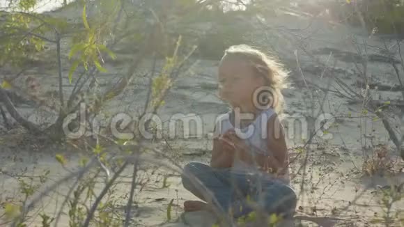 小女孩在沙漠里冥想日落时坐在沙滩上的孩子温暖视频的预览图