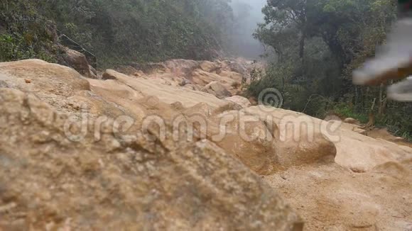 穿着雨衣的年轻人在旅途中在岩石小径上跳跃和慢跑徒步旅行者背着背包在石头地上奔跑视频的预览图