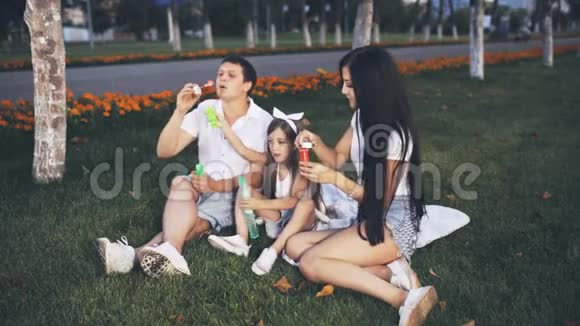 带着父母在草坪上吹肥皂泡的小女孩视频的预览图