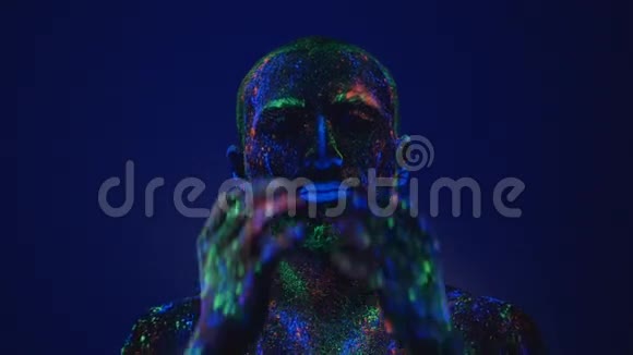 一个人在紫外线下从脸上擦荧光粉在生活环境前的空虚视频的预览图