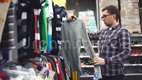 戴眼镜的成年人在商店里挑选一件毛衣视频的预览图