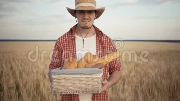 年轻的农民站在麦田边手里拿着面包篮视频的预览图