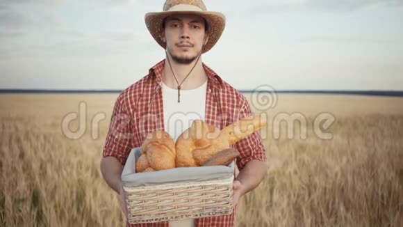 年轻的农民站在麦田边手里拿着面包篮视频的预览图