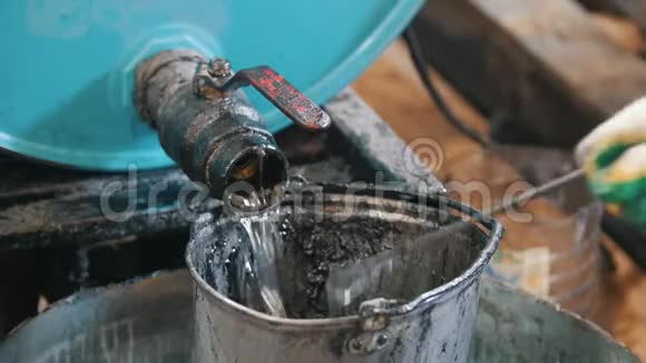 工人把发动机油或化学液体倒入旧的刮水桶中视频的预览图